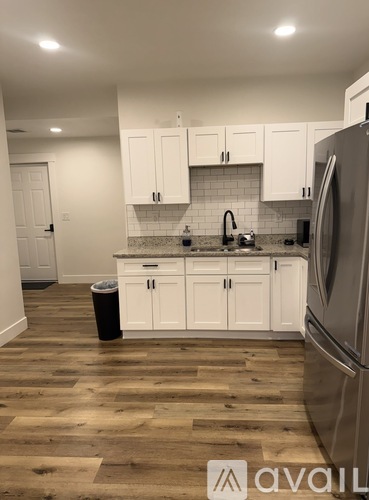 A kitchen with white cabinets and a wooden floor.