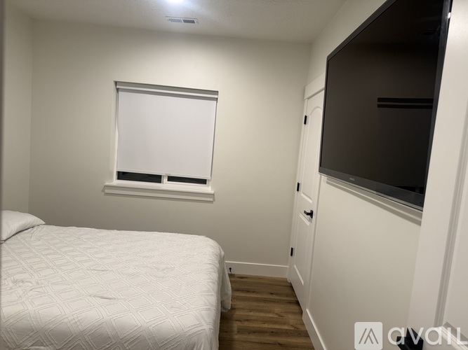 A bedroom with a bed, a window with blinds, and a cabinet with a microwave.