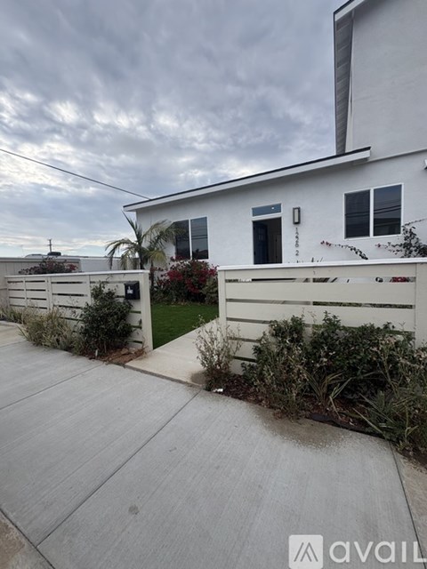 A white house with a grey driveway and a sign that says "available".