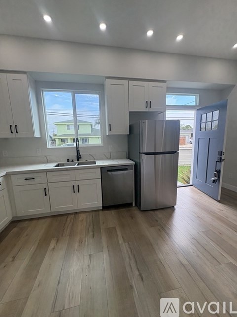 A kitchen with white cabinets and a wooden floor.