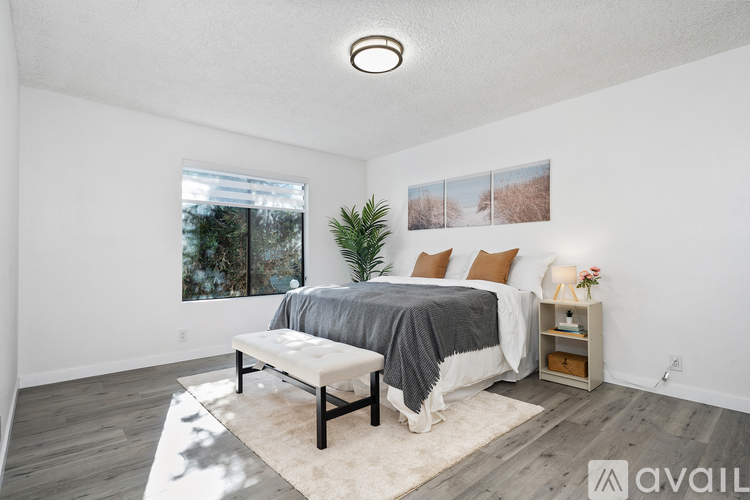 A bedroom with a bed, a bench, and a potted plant.