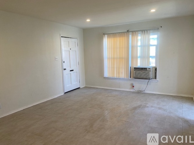 A spacious room with a door, window, and a wall-mounted air conditioning unit.