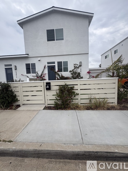A white house with a black gate and a small garden in front.