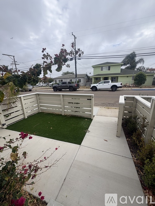 A backyard with a white fence and a green lawn.