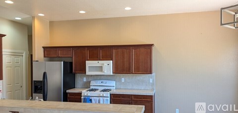 A kitchen with wooden cabinets and a black refrigerator.