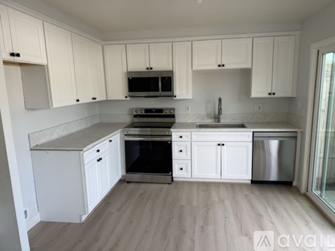 A kitchen with white cabinets and a wooden floor.