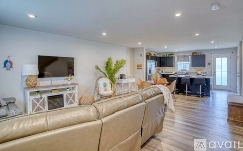 A living room with a beige couch and a television on a white stand.