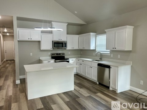 A kitchen with white cabinets and a wooden floor.