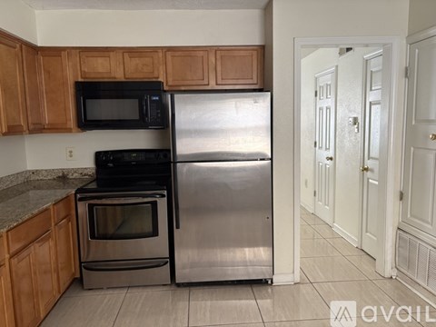 A kitchen with wooden cabinets and a stainless steel refrigerator.