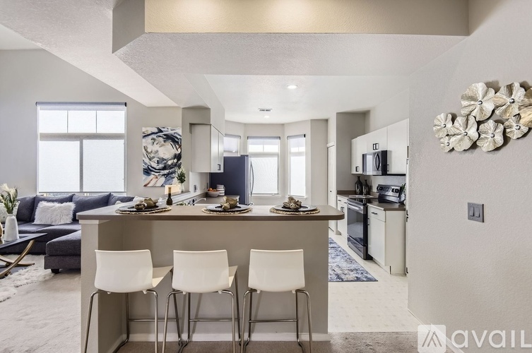 A modern kitchen with white chairs and a dining table set for four.