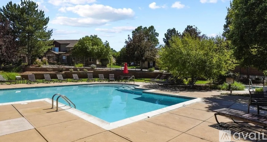 A large outdoor swimming pool surrounded by trees and lounge chairs.