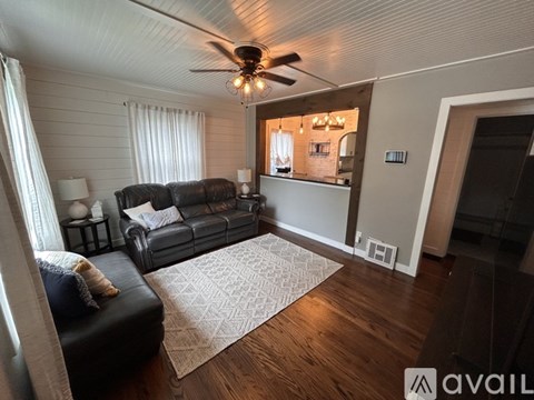 A living room with a black couch and a ceiling fan.