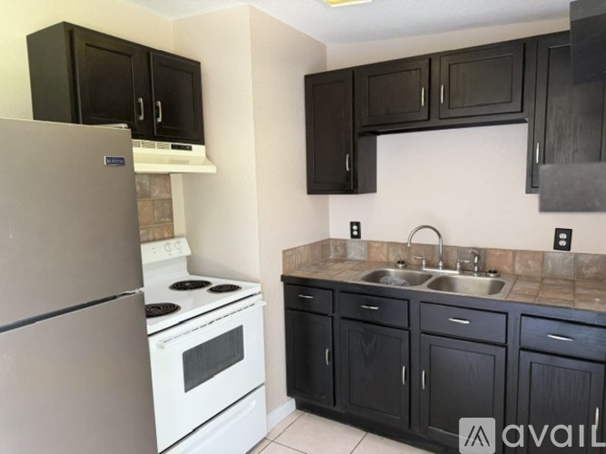 A kitchen with black cabinets and a white stove top oven.