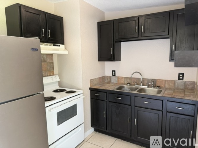 A kitchen with black cabinets and a white refrigerator.