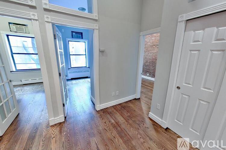 A room with wooden floors and white walls, with a door in the background.