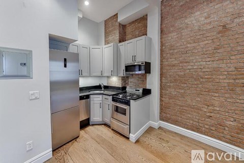 A kitchen with a brick wall and wooden floors.