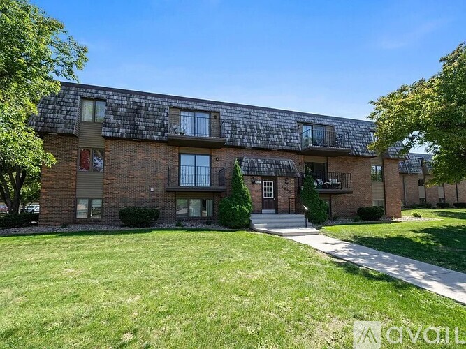 A brick apartment building with a green lawn in front.