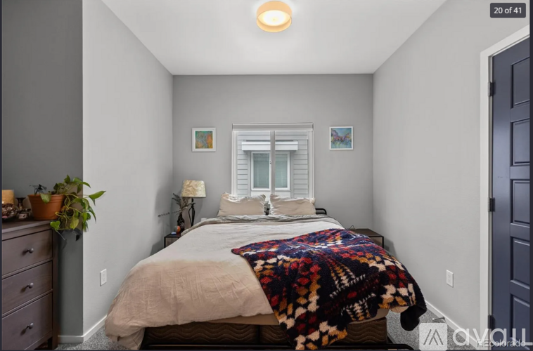 A bedroom with a bed covered in a multicolored blanket.