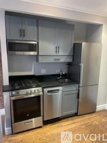 A kitchen with stainless steel appliances and wooden flooring.