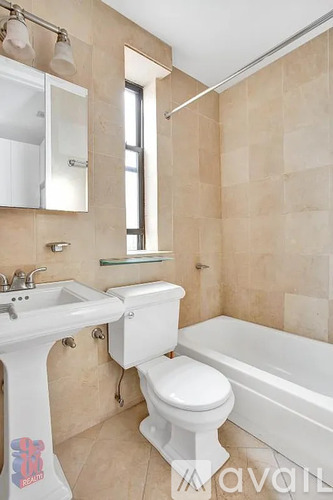 A white toilet sits in a bathroom with beige tiles.