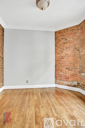 A room with a wooden floor and a brick wall.