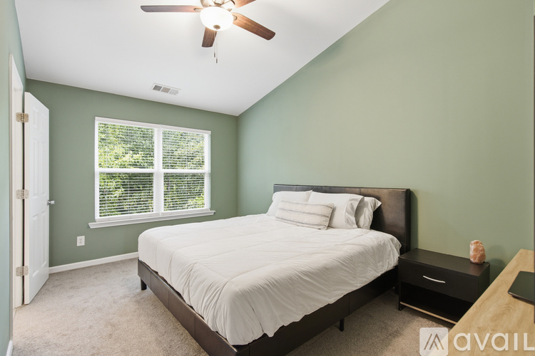 A bedroom with a bed, nightstand, and window.