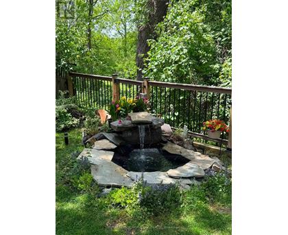 A small waterfall in a garden surrounded by a fence.