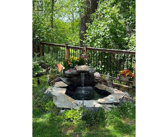 A small waterfall in a garden surrounded by a fence.