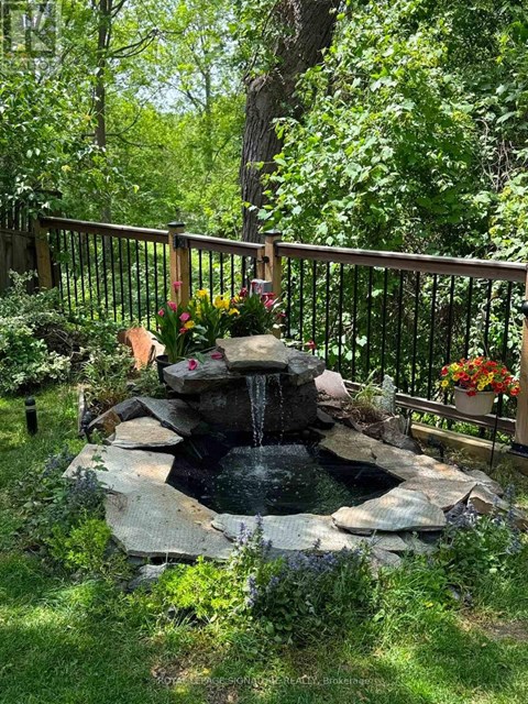 A small waterfall in a garden surrounded by a fence.