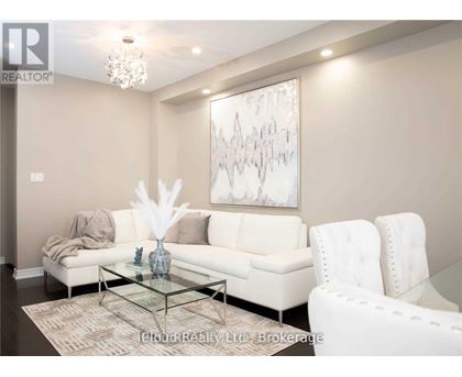 A living room with a white couch, a glass coffee table, and a large abstract painting on the wall.