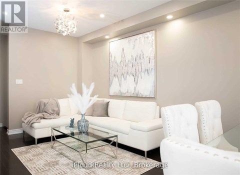 A living room with a white couch, a glass coffee table, and a large abstract painting on the wall.