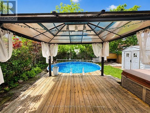 A wooden deck with a pool under a canopy.