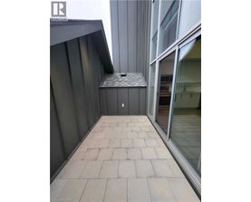 A balcony with a grey tiled floor and a glass door.