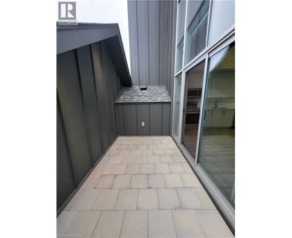 A balcony with a grey tiled floor and a glass door.