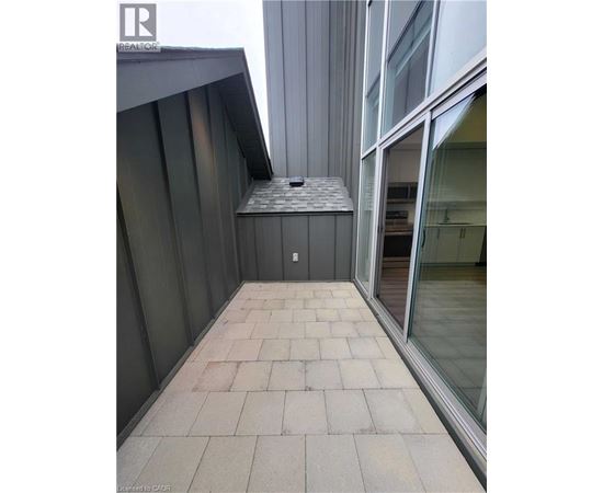 A balcony with a grey tiled floor and a glass door.