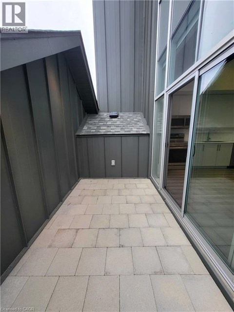 A balcony with a grey tiled floor and a glass door.