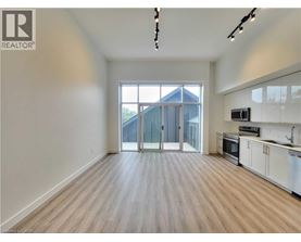 A spacious, empty room with wooden flooring and a large window.