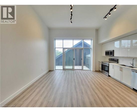 A spacious, empty room with wooden flooring and a large window.