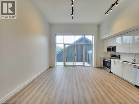 A spacious, empty room with wooden flooring and a large window.