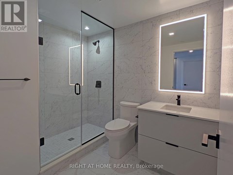 A bathroom with a toilet, sink, and mirror.