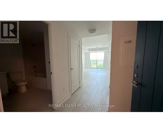 A room with a toilet, sink, and a door leading to a hallway.