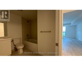 A white bathroom with a toilet, tub, and a doorway leading to another room.