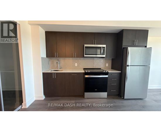 A kitchen with a refrigerator, microwave, and oven.