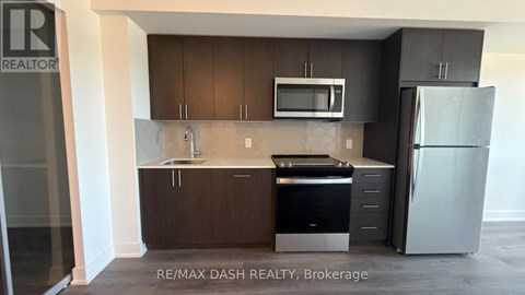 A kitchen with a refrigerator, microwave, and oven.