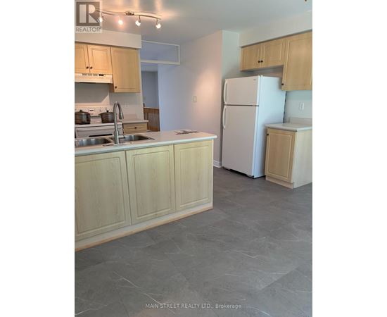 A kitchen with a sink, refrigerator, and cabinets.