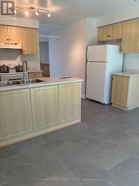 A kitchen with a sink, refrigerator, and cabinets.