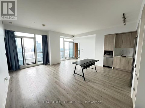 A spacious living room with a dining table and a view of the city through the windows.