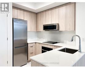 A modern kitchen with a refrigerator, microwave, and stove top oven.