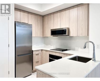 A modern kitchen with a refrigerator, microwave, and stove top oven.