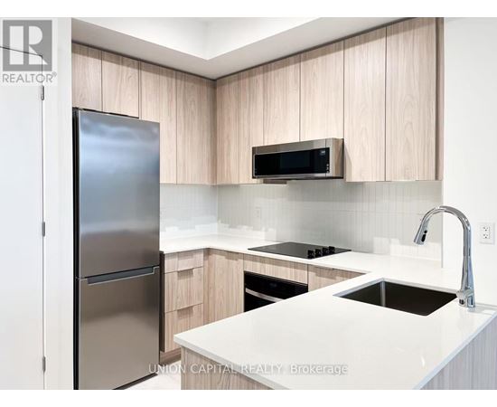 A modern kitchen with a refrigerator, microwave, and stove top oven.